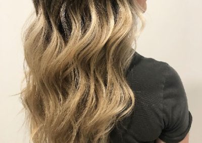 Woman with highlights and wavy hair shows her health hydrated hair